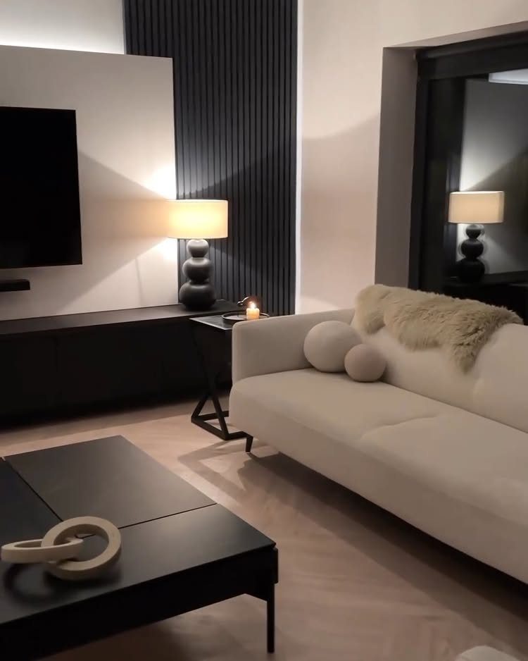 Modern living room with white sofa, black coffee table, and black slatted wall.