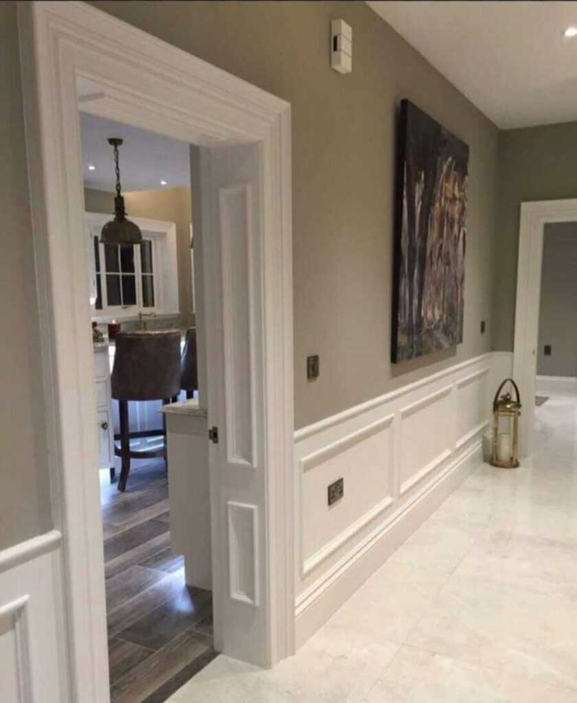 White decorative door trim and molding in a modern grey hallway with wainscoting.