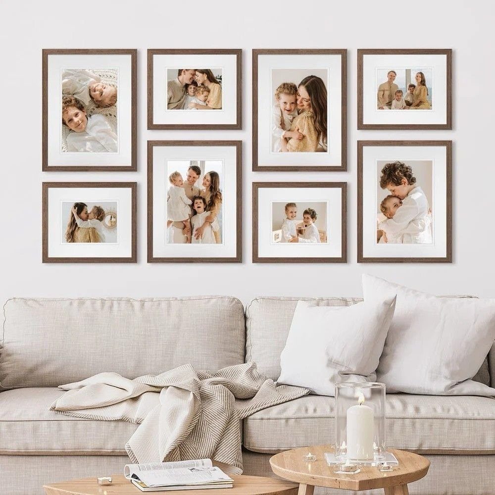 Gallery wall of framed family photos hanging above a neutral beige living room sofa.