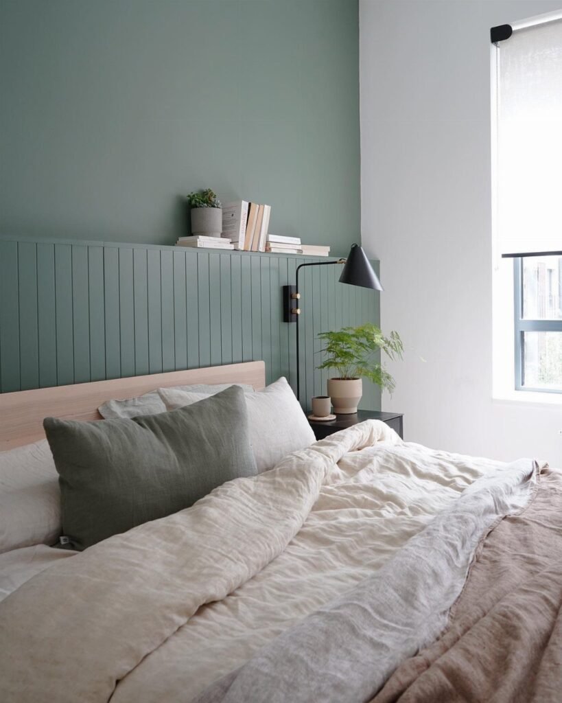 Bedroom with sage green walls and matching linens creating a calm atmosphere.