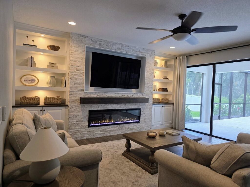 Modern living room with a white stone fireplace, mounted TV, and beige sofas.