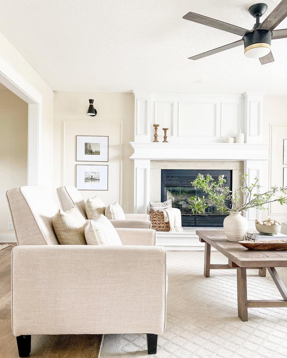Beige sofas and wooden coffee table arranged in a bright living room with fireplace.