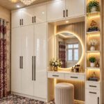 White built-in wardrobe and vanity with circular mirror and beige velvet stool