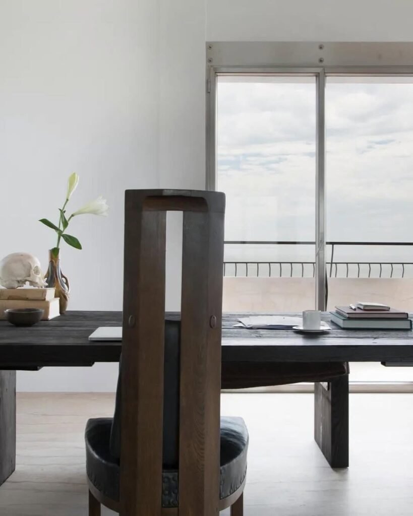 Dark wooden dining table and high-back chair in a minimalist white interior room