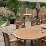 Round wooden dining table and chairs on a patio under a white umbrella
